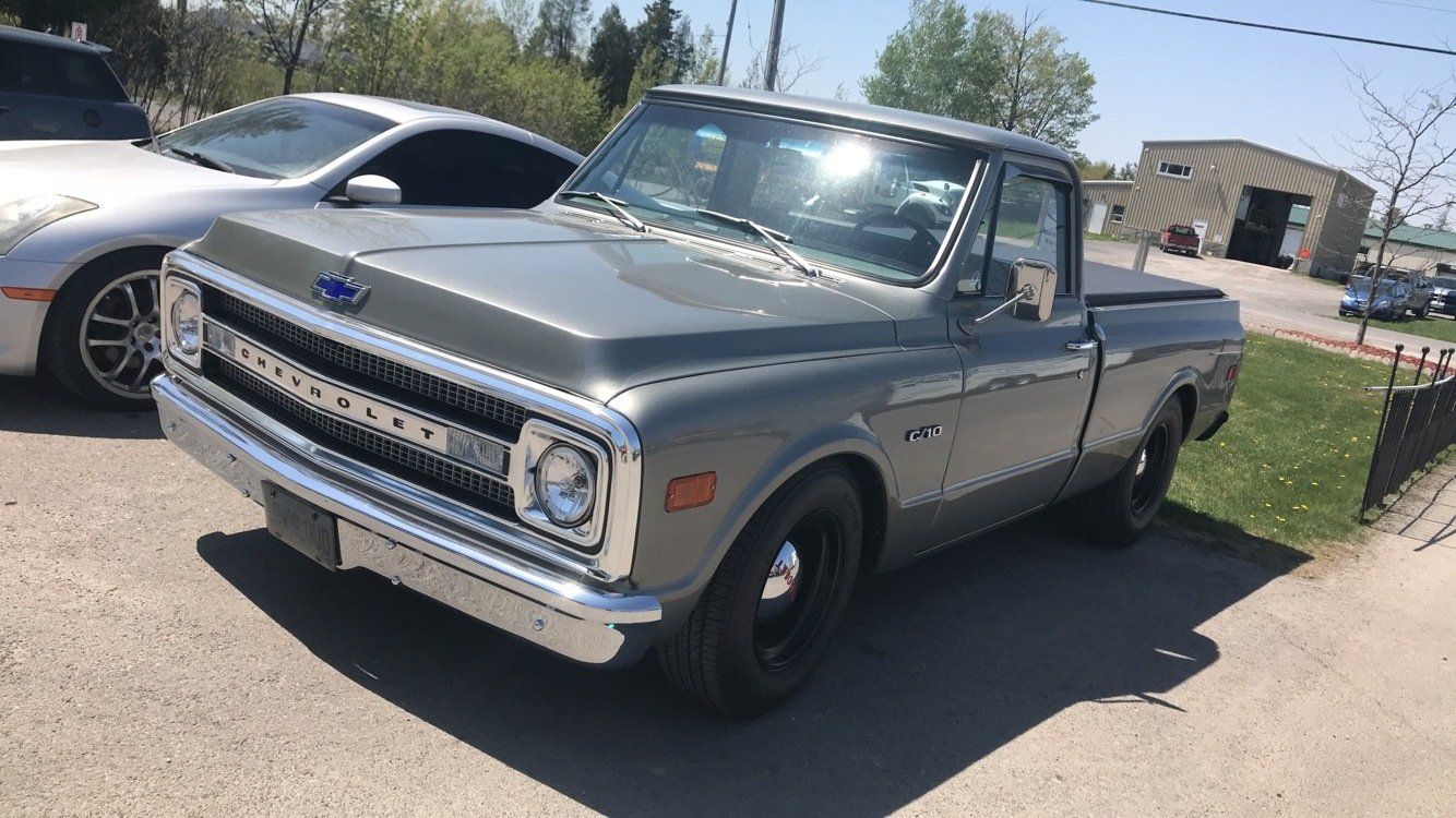 A gray truck is parked on the side of the road next to a white car.