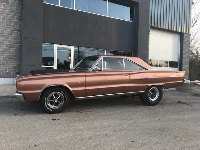 A brown car is parked in front of a building.