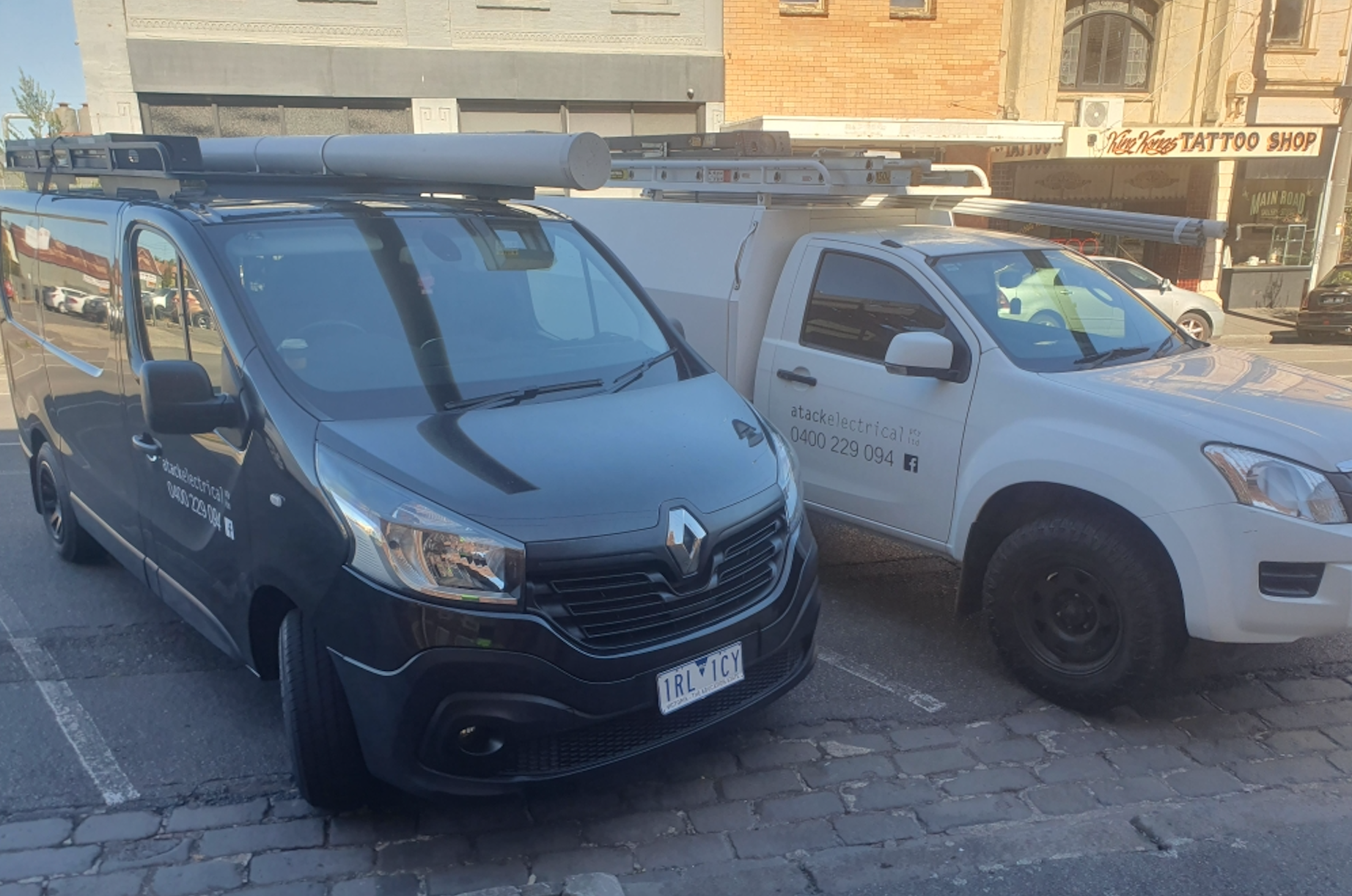 Two White Trucks Are Parked In Street — Atack Electrical in Ballarat, VIC