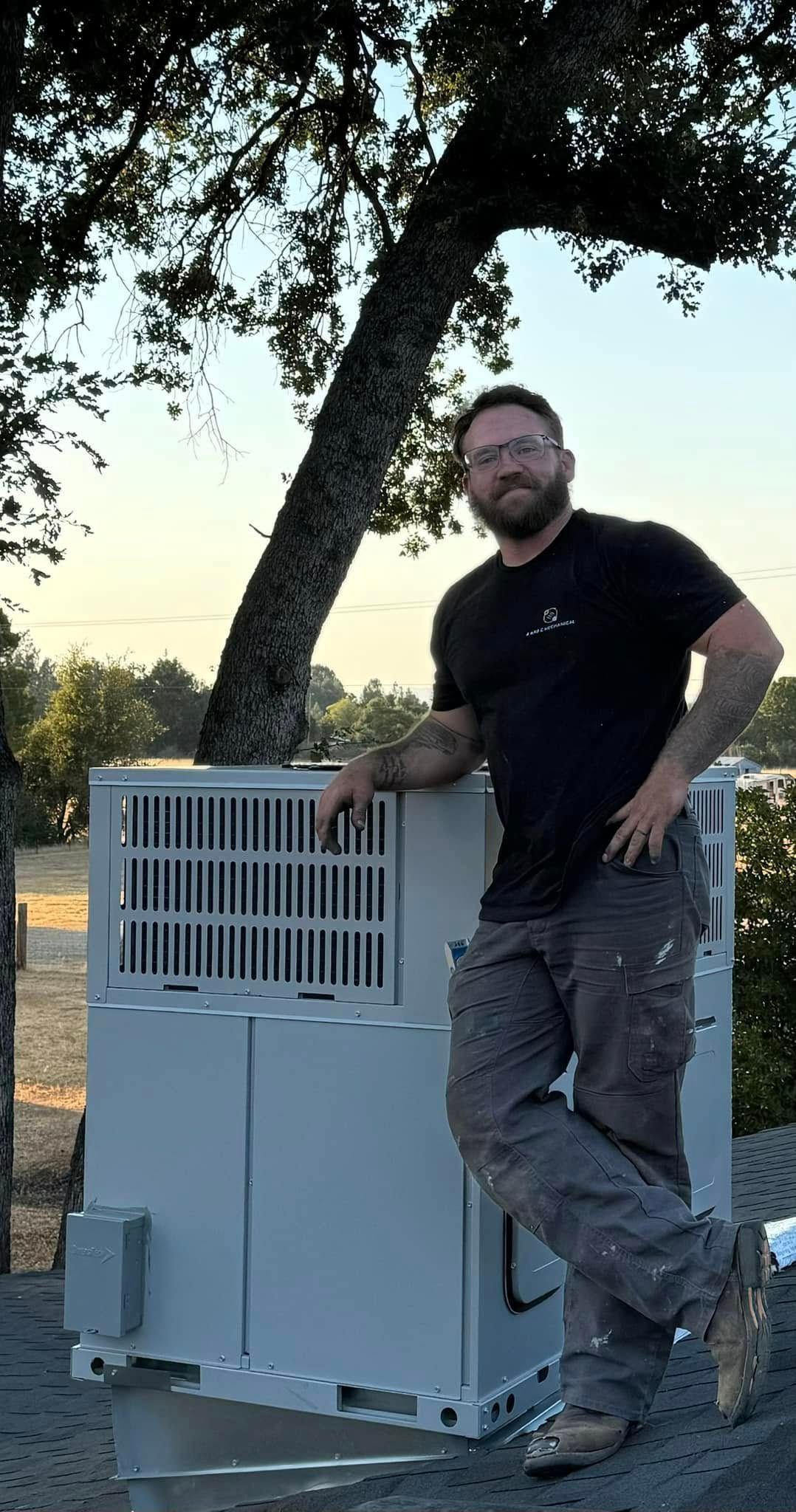 A man is standing next to a dog cage under a tree.