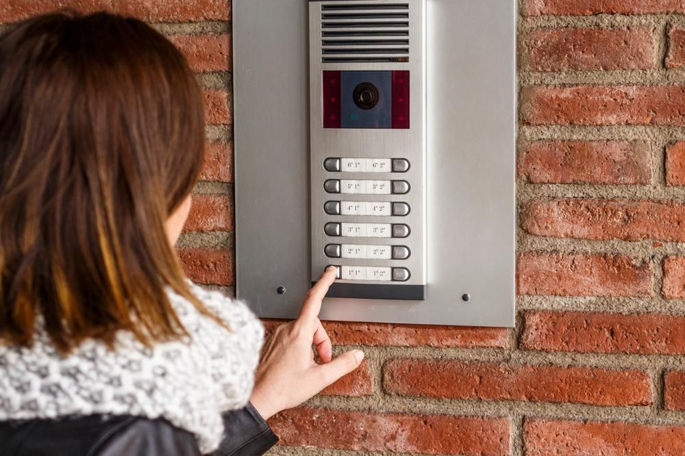 A Woman Is Pressing a Button on A Doorbell — MNC Security in Nambucca Heads, NSW