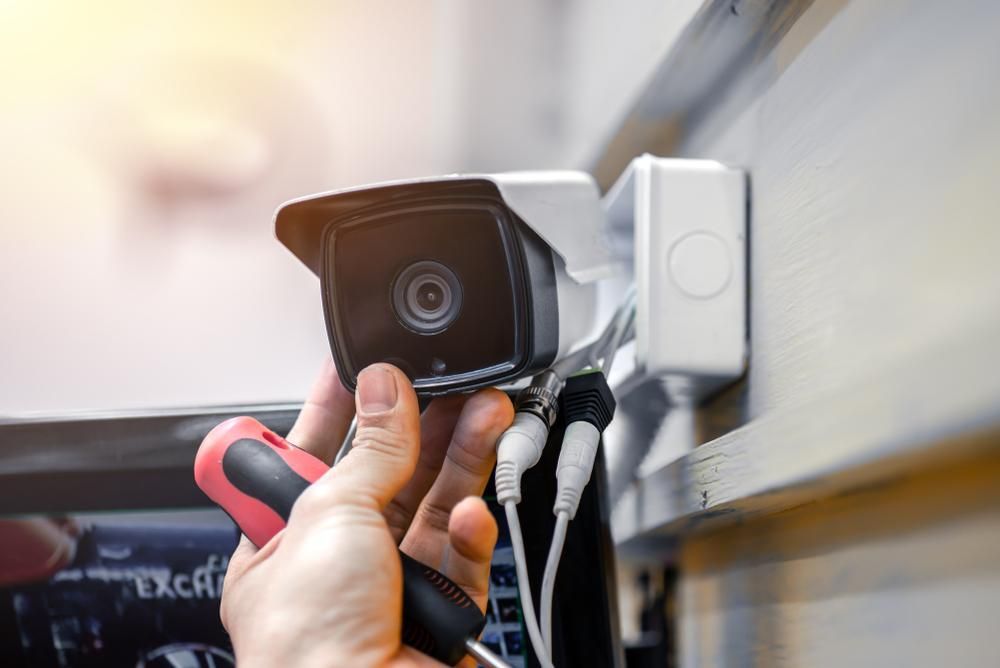 A Person Is Installing a Security Camera on A Wall — MNC Security in Sawtell, NSW
