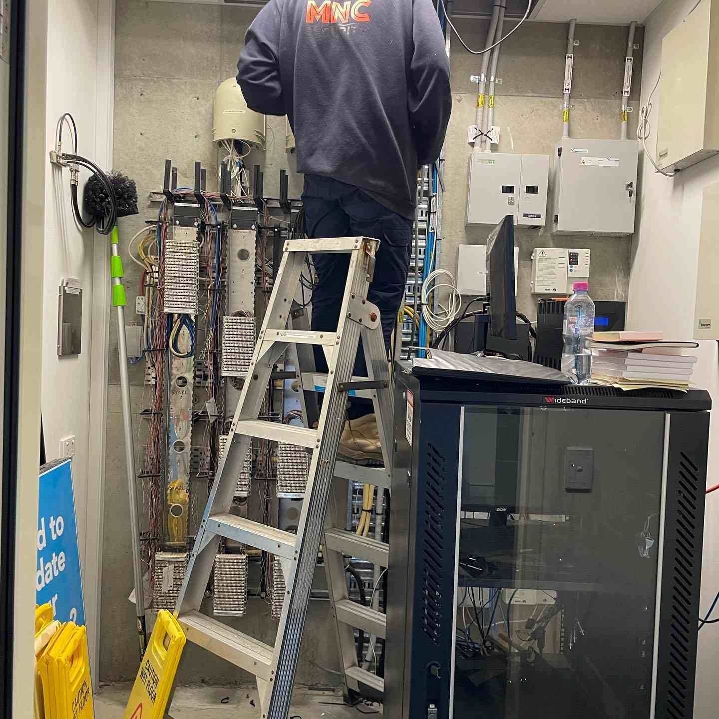 A Man Is Standing on A Ladder in A Room — MNC Security in Sawtell, NSW