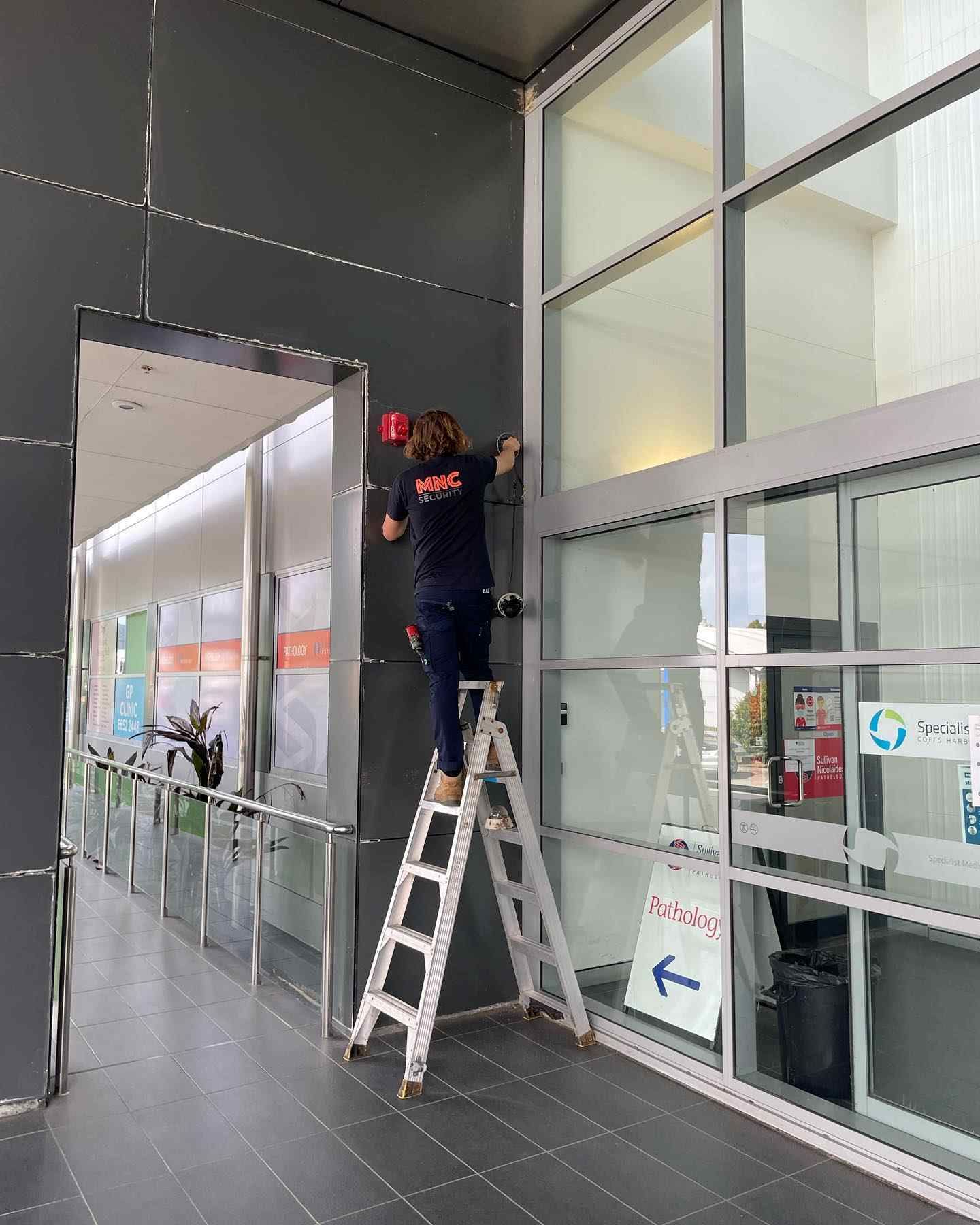 A Woman Is Standing on A Ladder — MNC Security in Sawtell, NSW