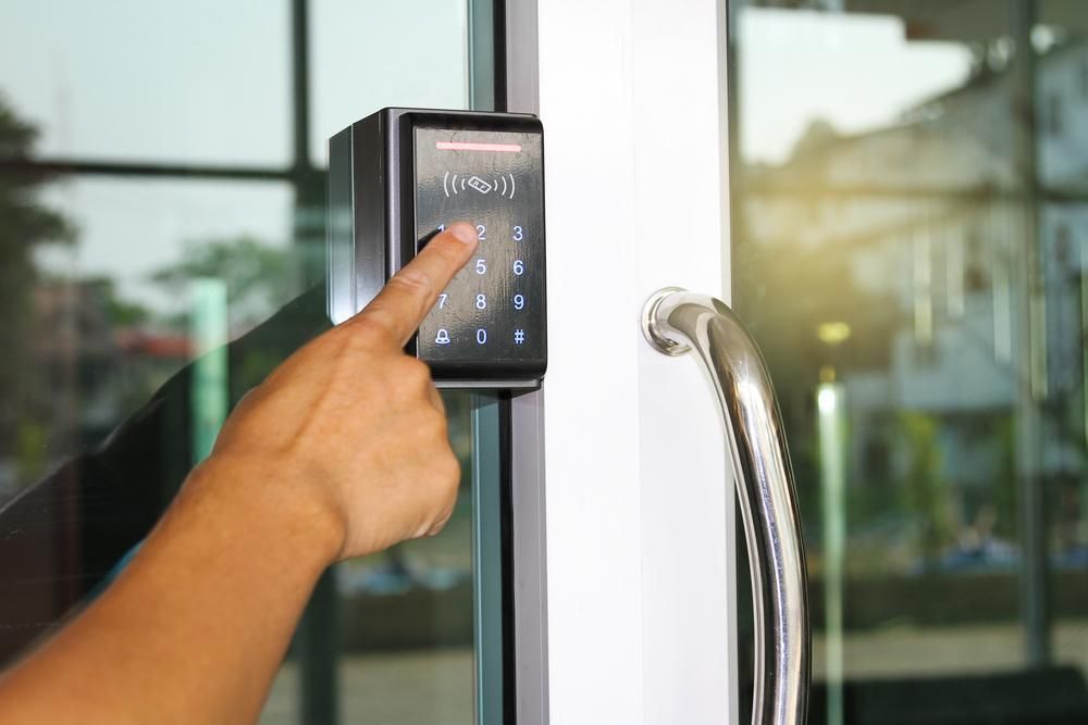 A Person Is Using a Keypad to Open a Glass Door — MNC Security in Toormina, NSW