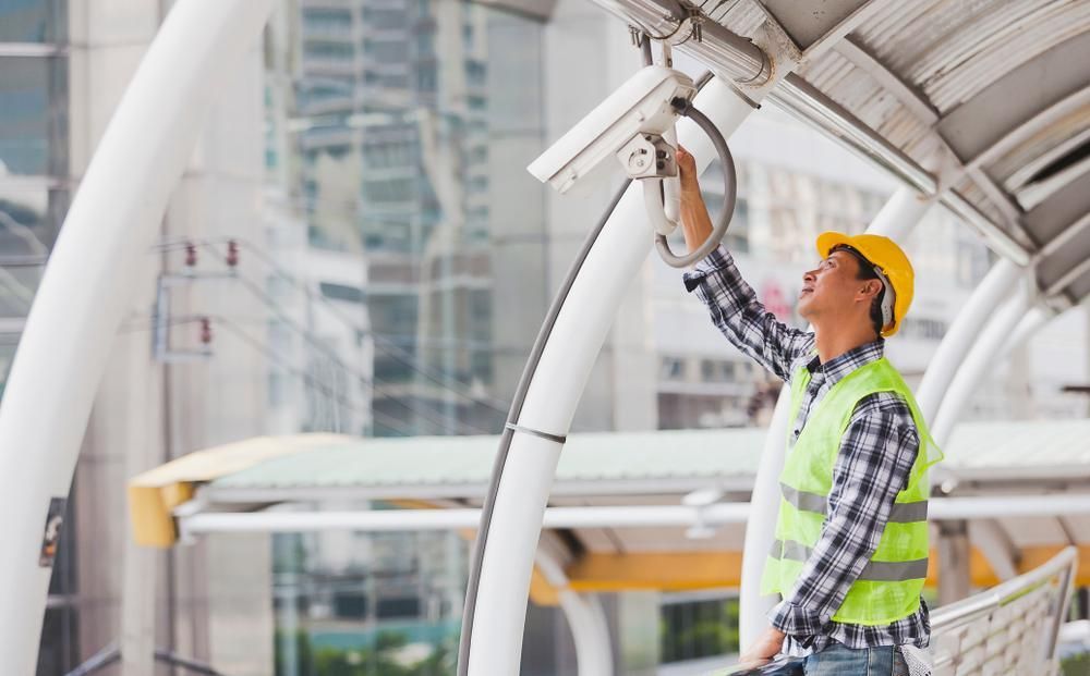 A Man Is Working on A Security Camera on A Bridge — MNC Security in Sawtell, NSW