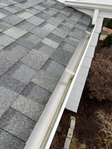 A close up of a gutter on a roof with shingles.