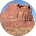Eroded, reddish-brown sandstone formations in a desert setting, with a blue sky visible.