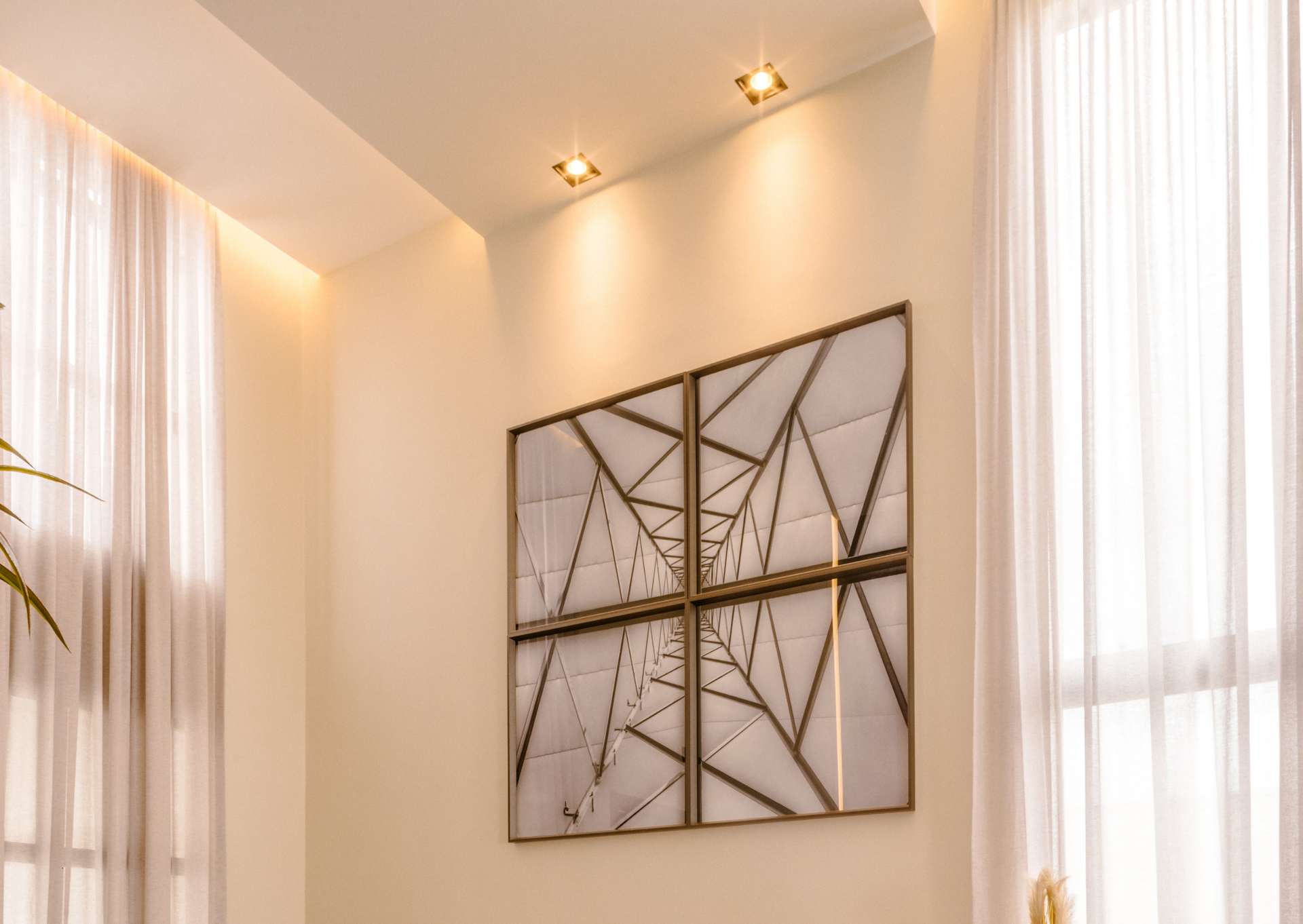 White room with geometric artwork on the wall. Soft light shines on the wall and curtains.