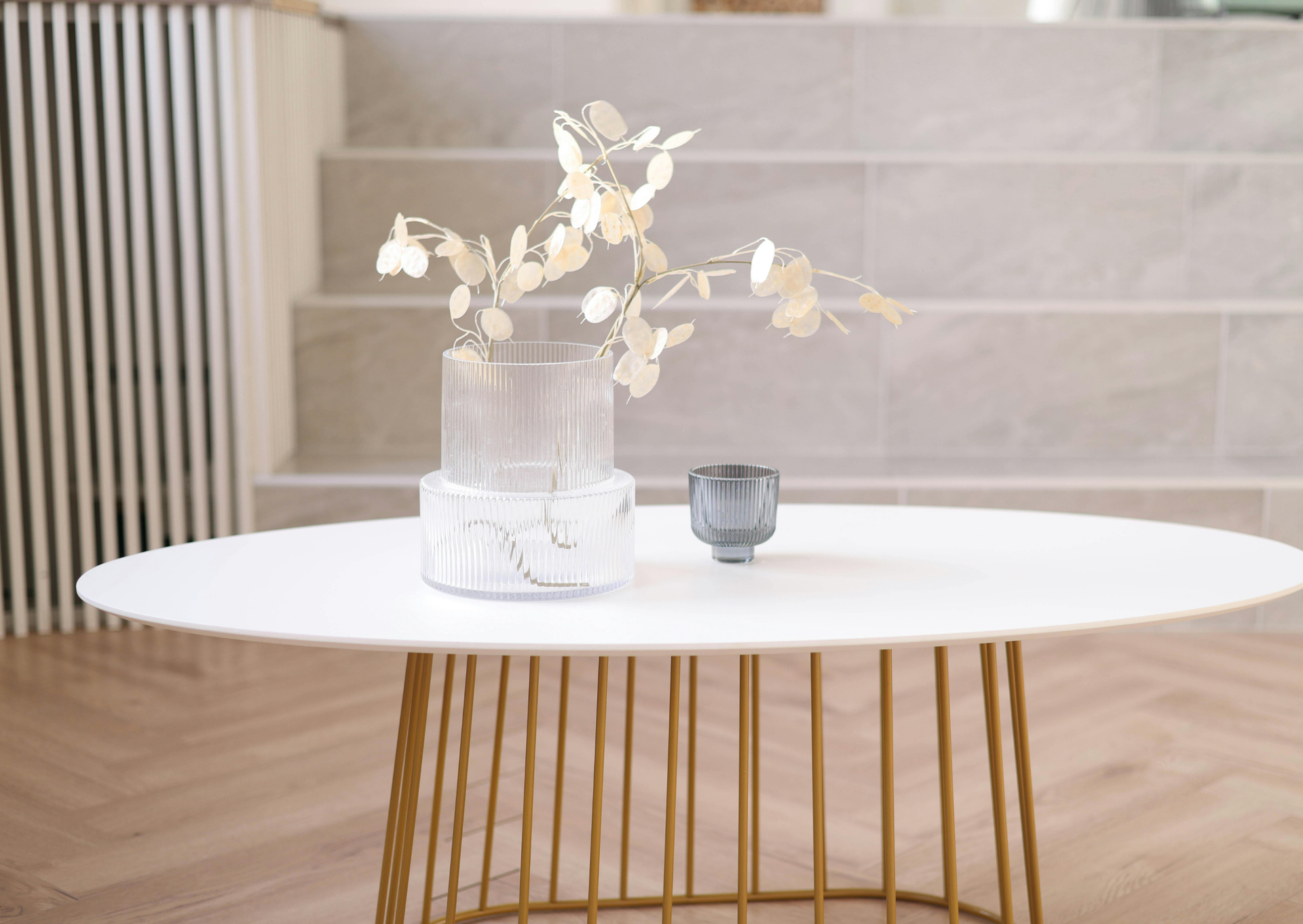 White coffee table with vase of gold branches and a small cup, indoors.
