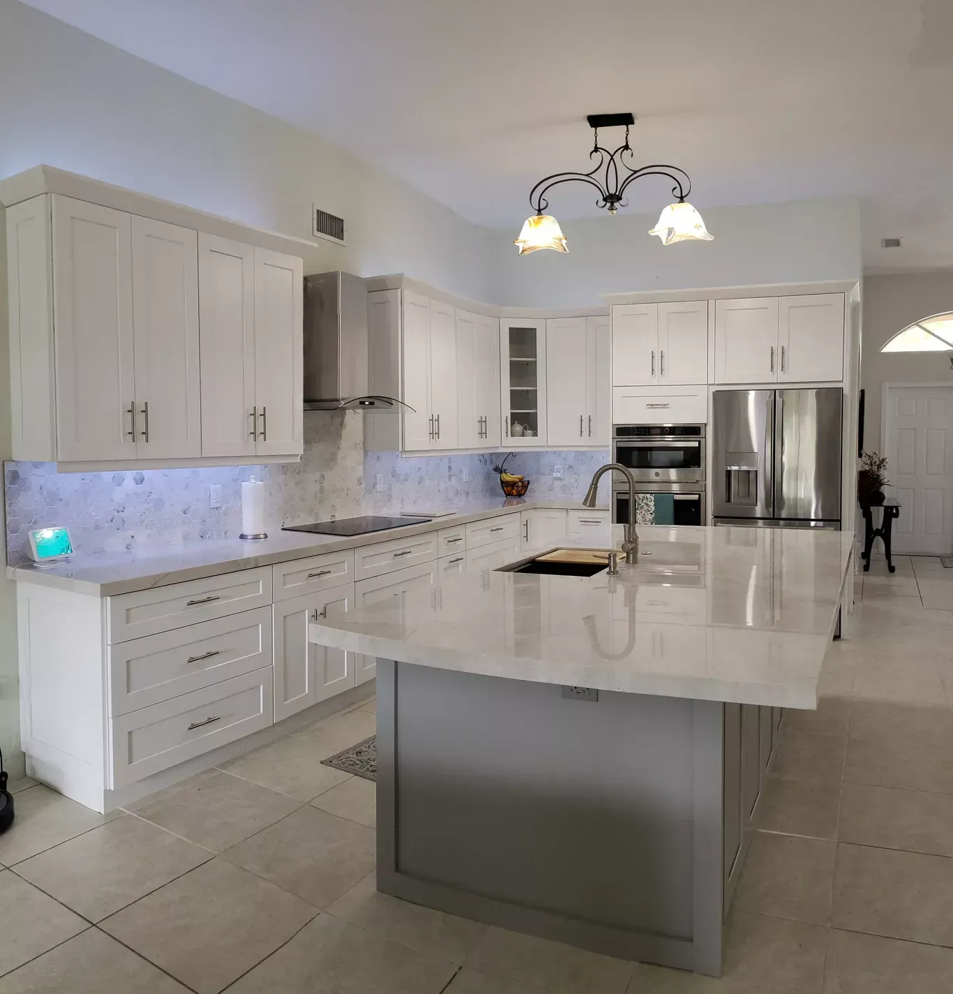 White kitchen with a large island, stainless steel appliances, and light gray accents.