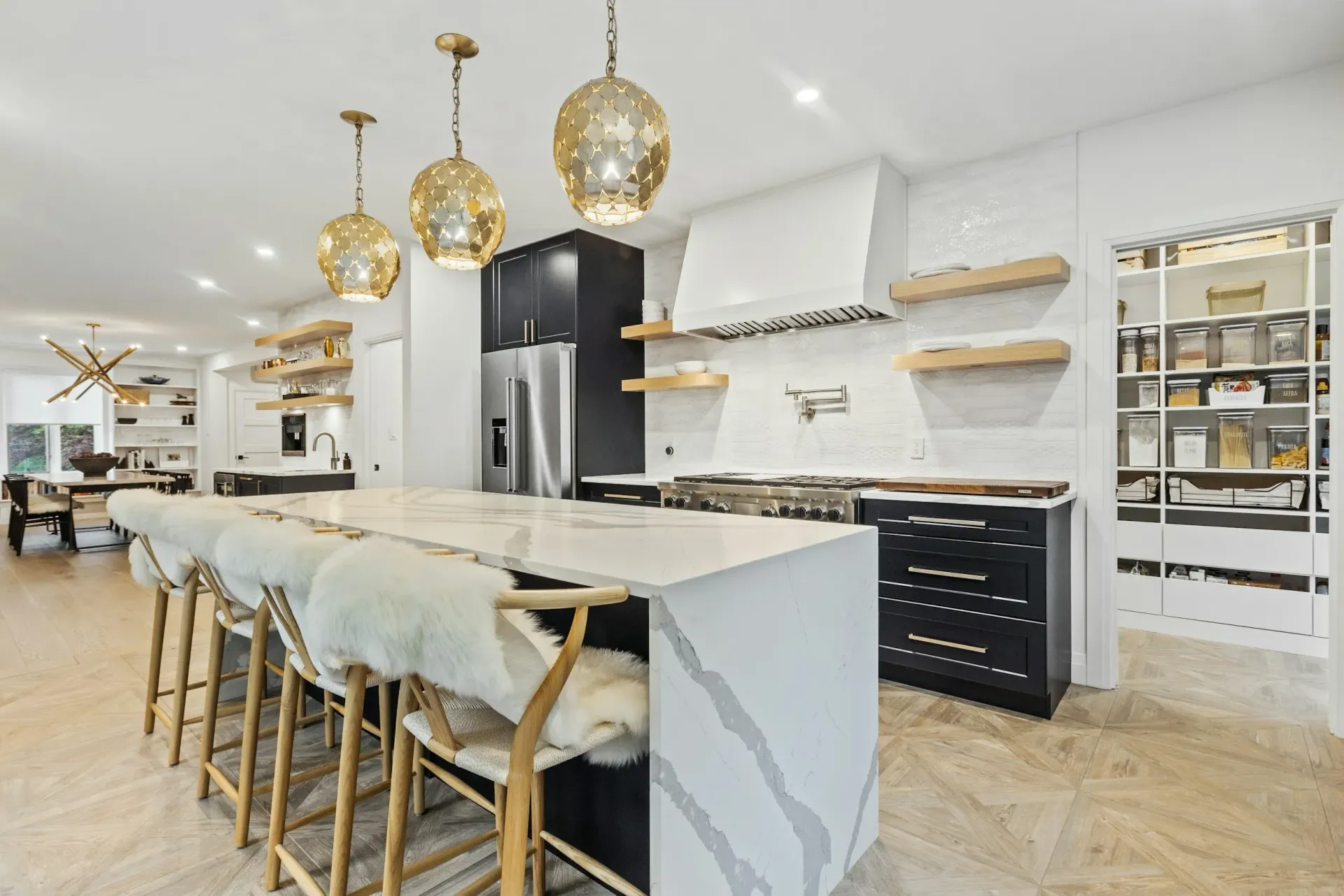 Modern kitchen with island, gold pendant lights, white countertops, and a pantry.