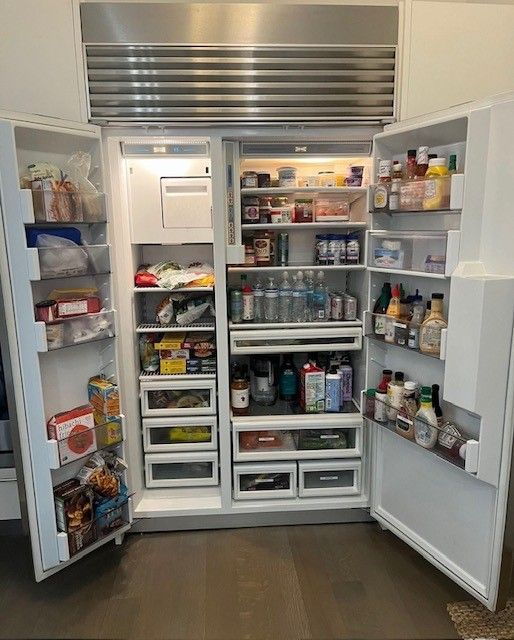 A man is fixing a refrigerator with a screwdriver.