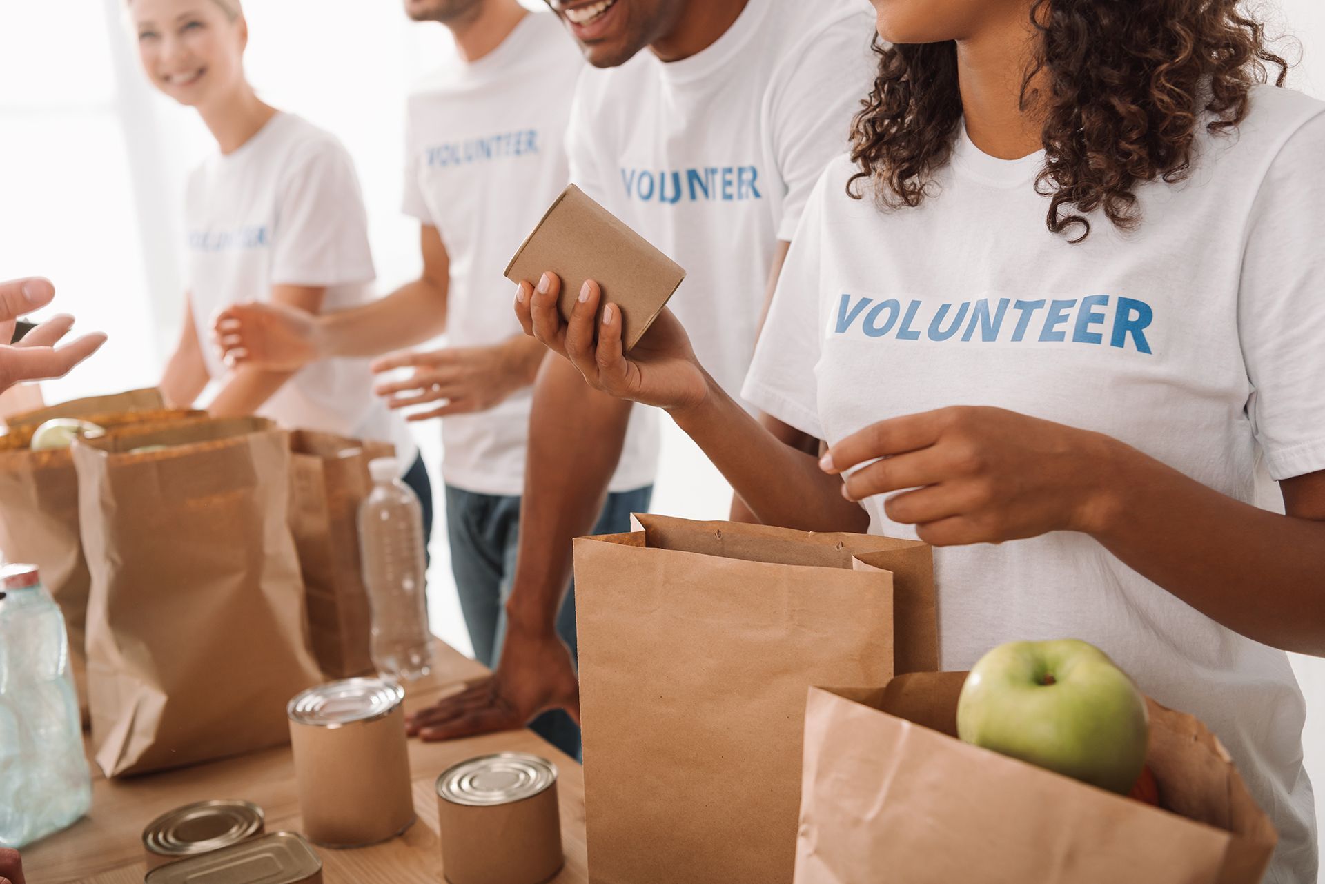 A group of volunteers are sitting at a table with bags of food.