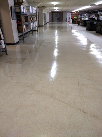 A long hallway in a building with a shiny floor and shelves.