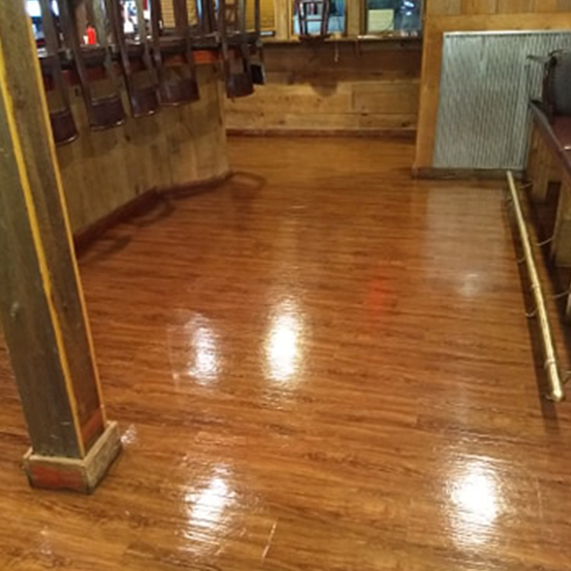 A wooden floor in a room with a bar and chairs.