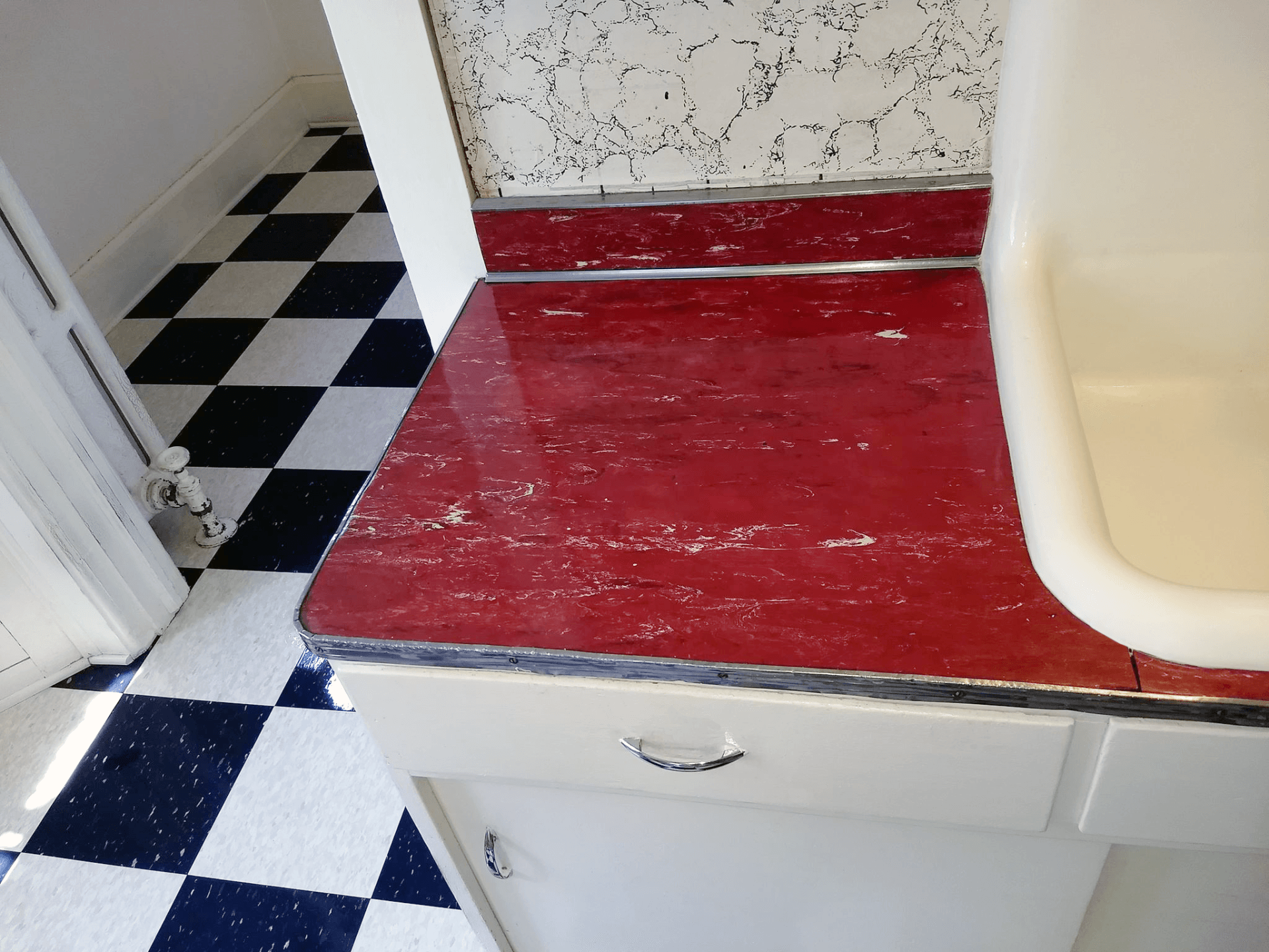 A bathroom with a red counter top and a checkered floor