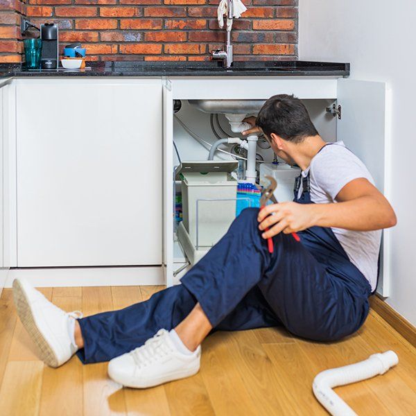 Plumber Fixing Under the Sink in the Kitchen — Sanford, FL — Hancock Plumbing Co Inc