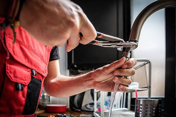 Repairman Using Adjustable Pliers to Fix Kitchen Faucet — Sanford, FL — Hancock Plumbing Co Inc
