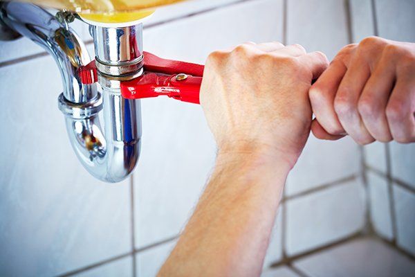 Plumber Hands Holding Wrench and Fixing a Sink in Bathroom — Sanford, FL — Hancock Plumbing Co Inc