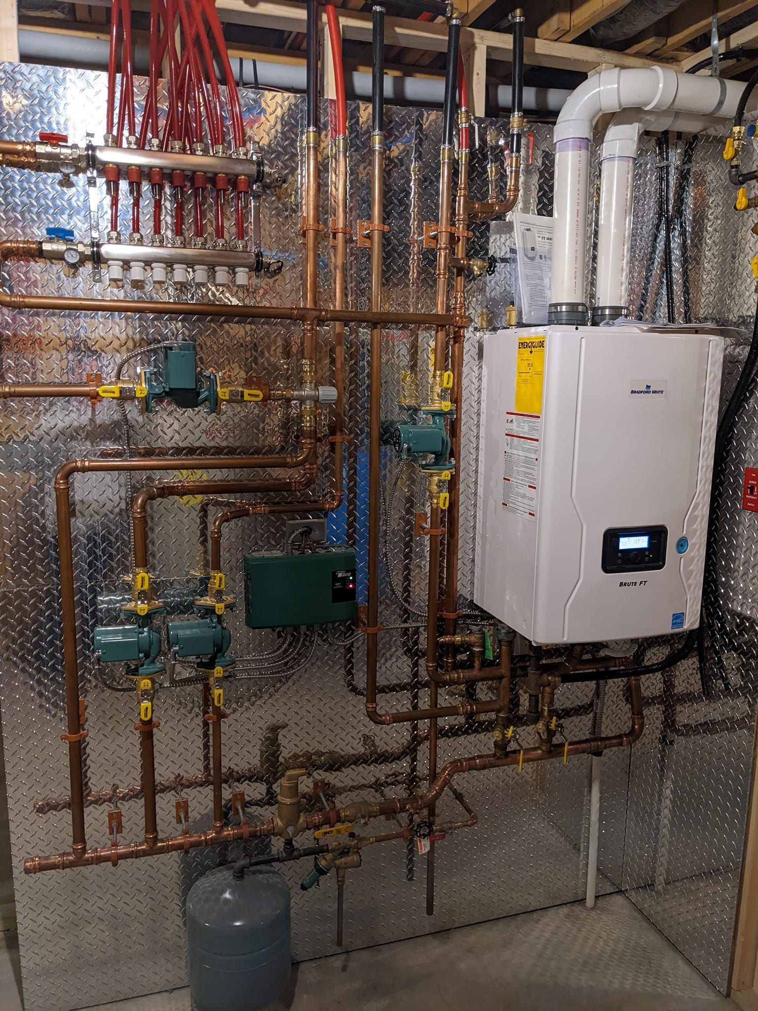 A room with a lot of pipes and a boiler on the wall.