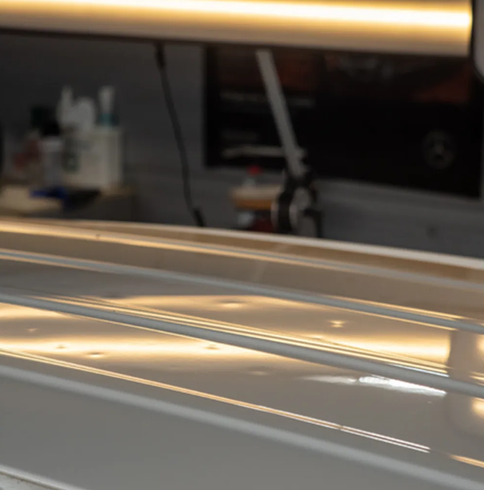 Shiny white car roof with reflections in a garage or workshop setting