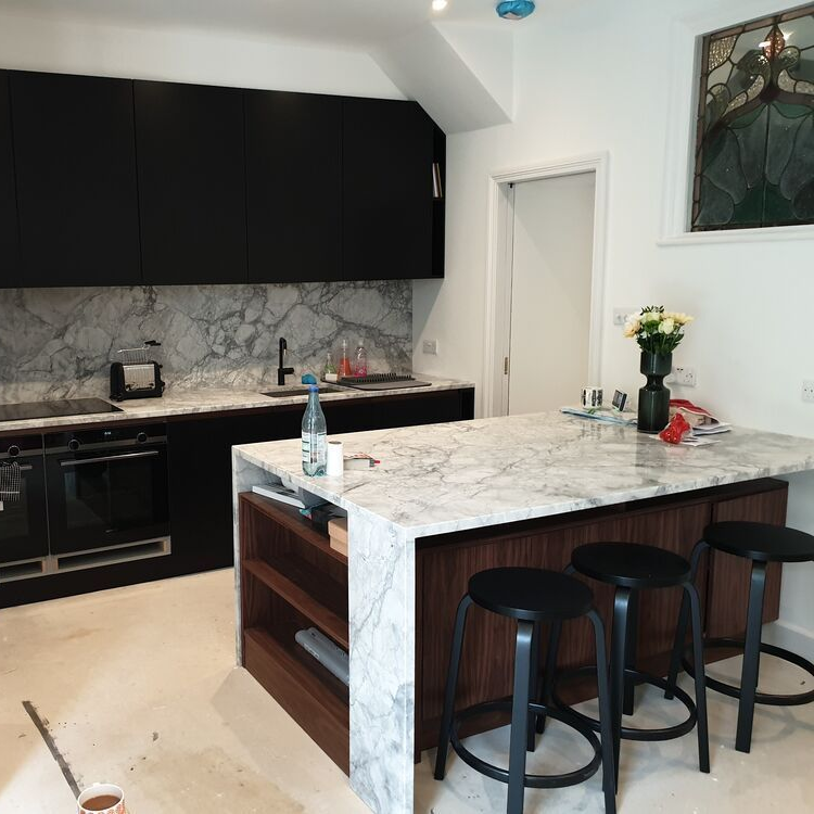 A kitchen with black cabinets and marble counter tops