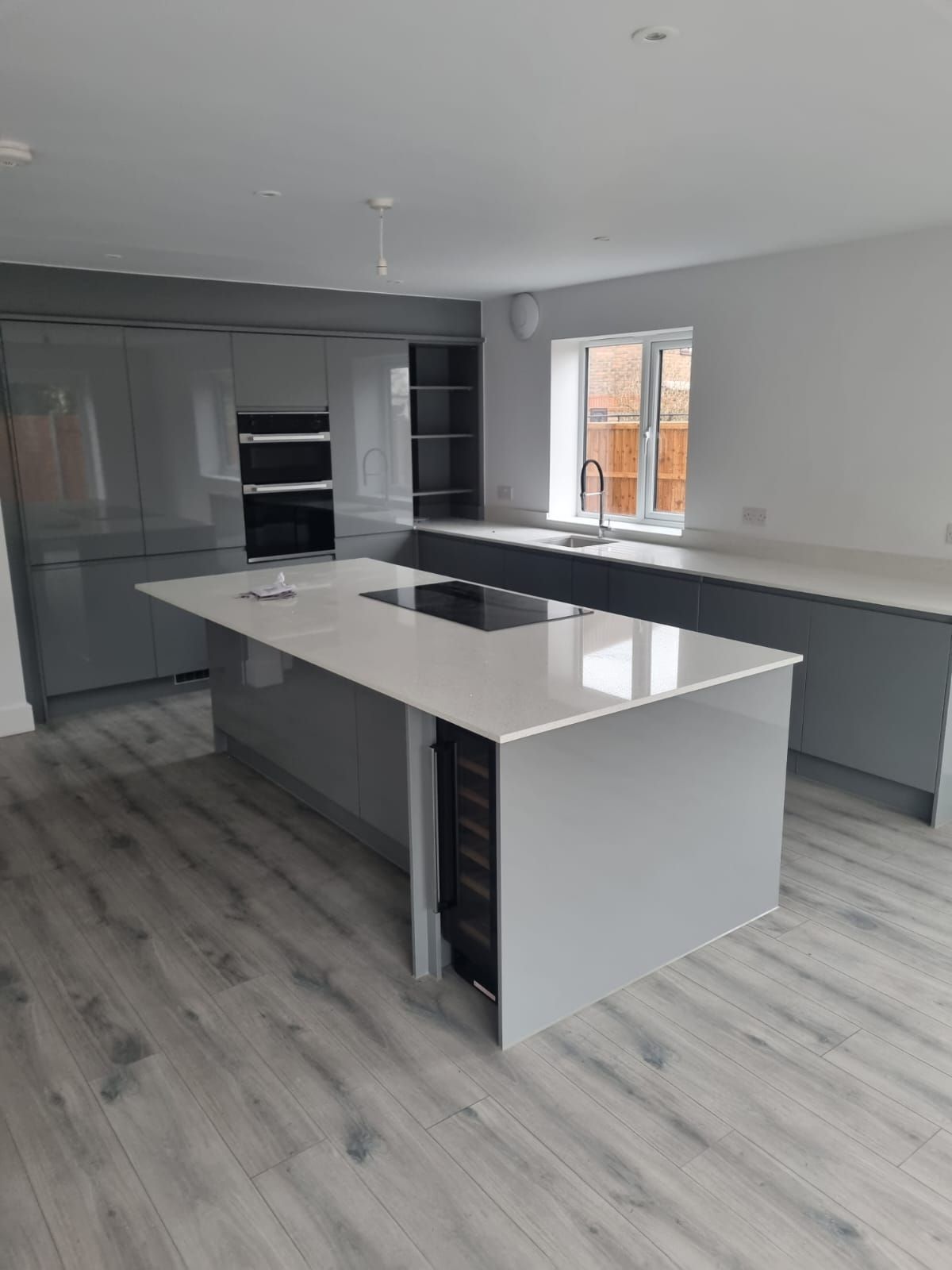 A kitchen with black cabinets and white counter tops and a vase of flowers on the counter.