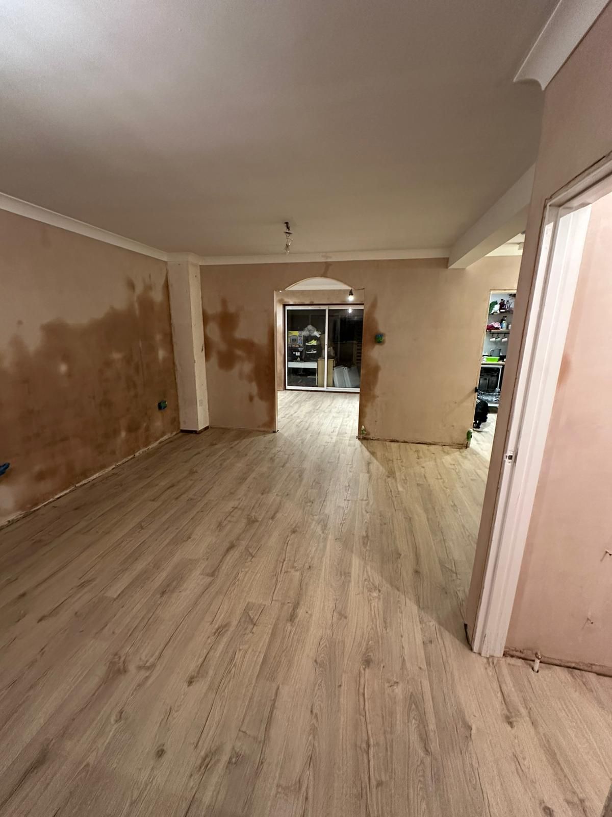 A man is working on a wall in a room with a skylight.