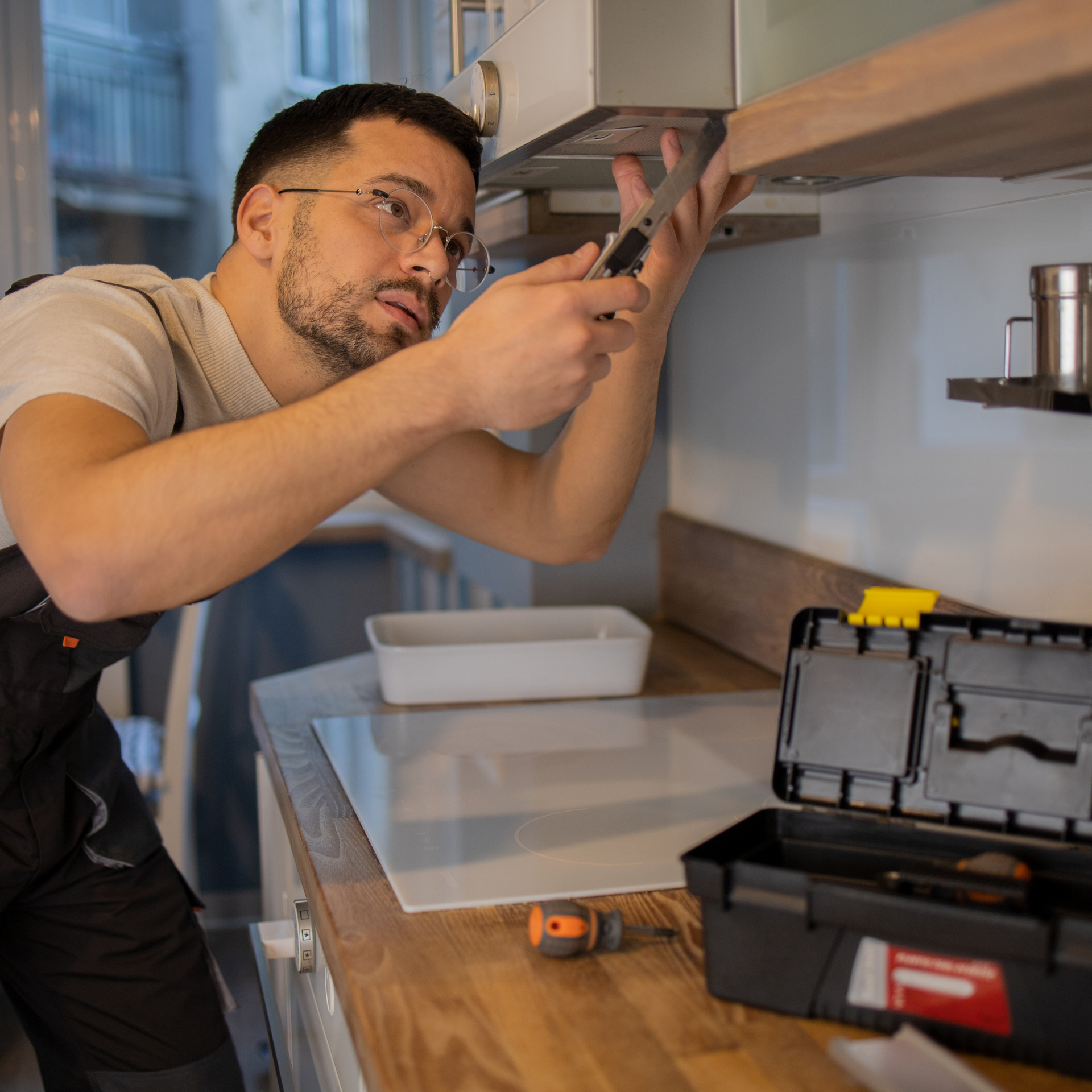 A man is working on a cabinet in a kitchen