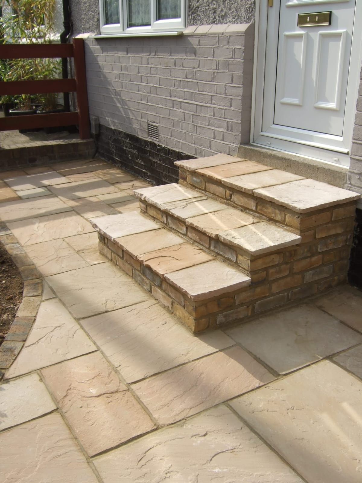 Stone steps leading to a white door, set in a paved pathway.