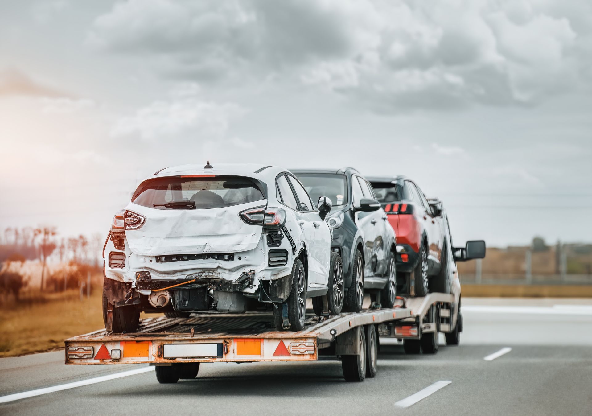 A tow truck is carrying a row of cars on a highway.