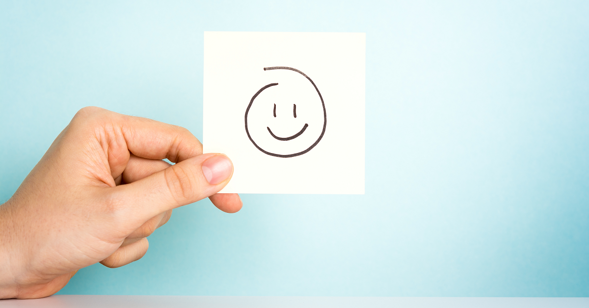 Overhead view: Person using laptop at desk with photo frames, notebook, phone, and stack of paper.