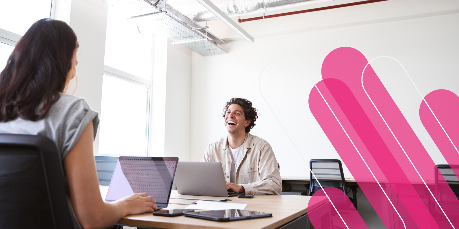 Businesspeople in suits at a white table shaking hands, in a modern, bright office setting.