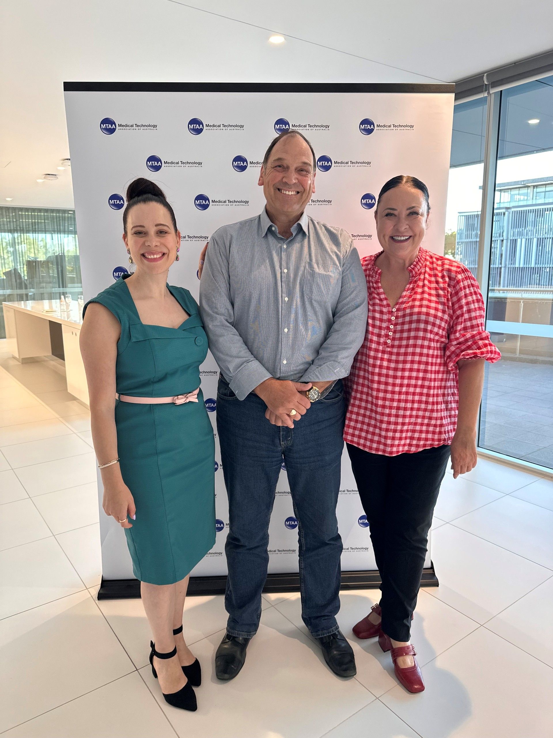 Five people pose in front of a 