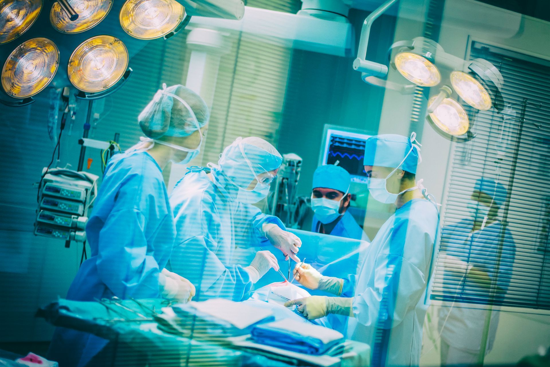 Medical team in blue scrubs operating in a brightly lit surgical room.