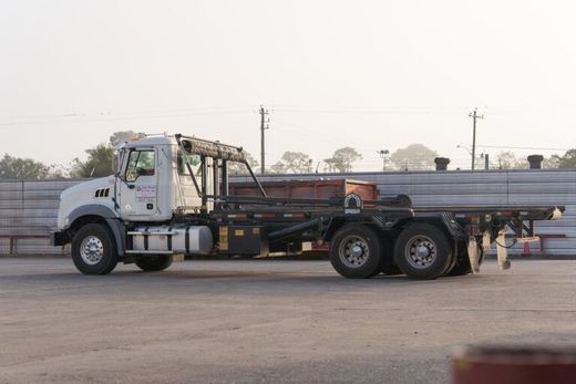 White tow truck parked in a lot, side view with black flatbed and dual rear axles