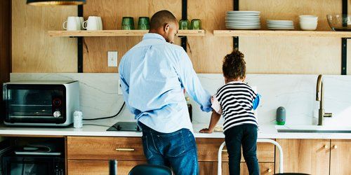 father and daughter standing near kitchen sink