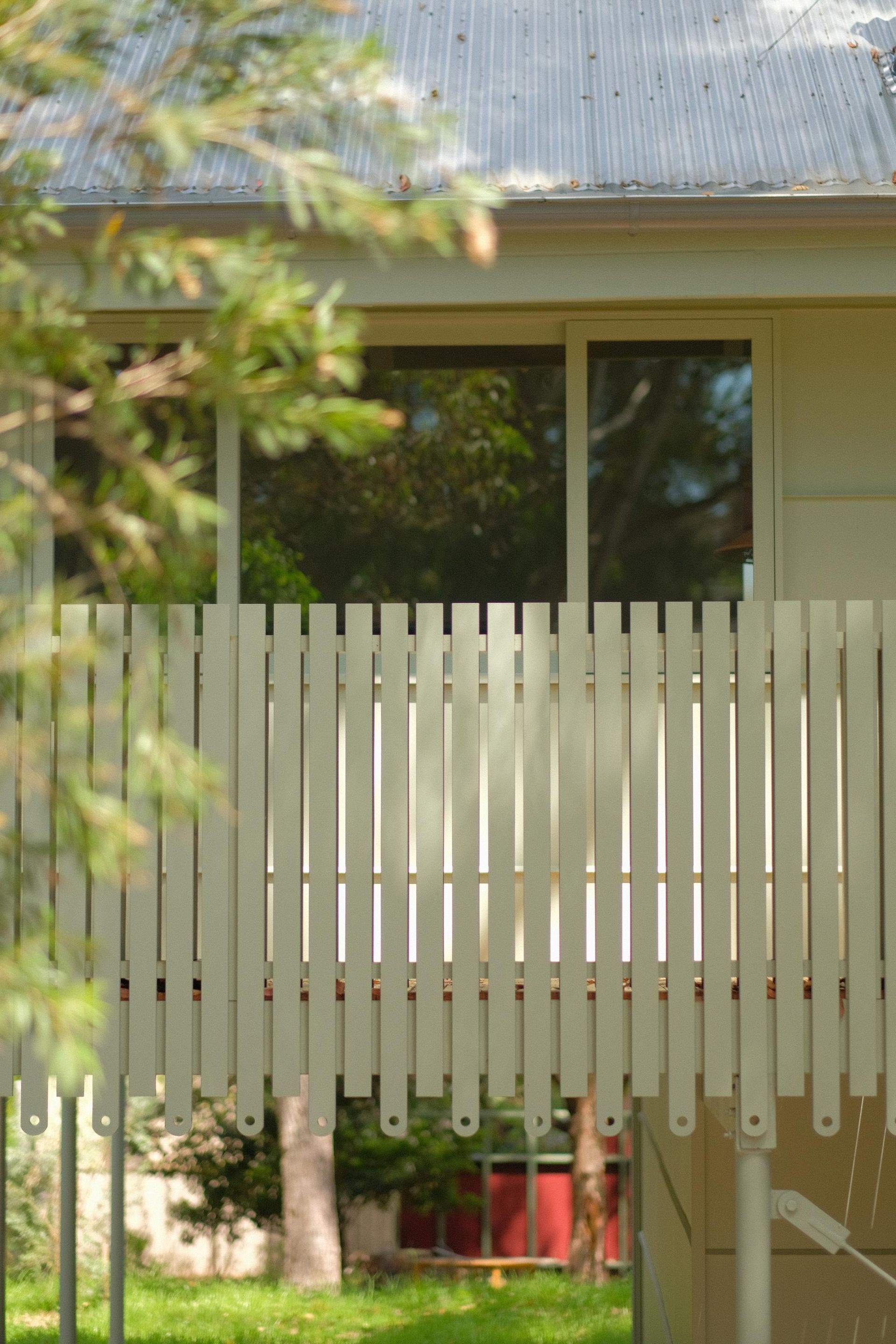 A White Picket Fence in Front of a House With Green Grass — Envisage Construction and Design in Meadowbank, NSW