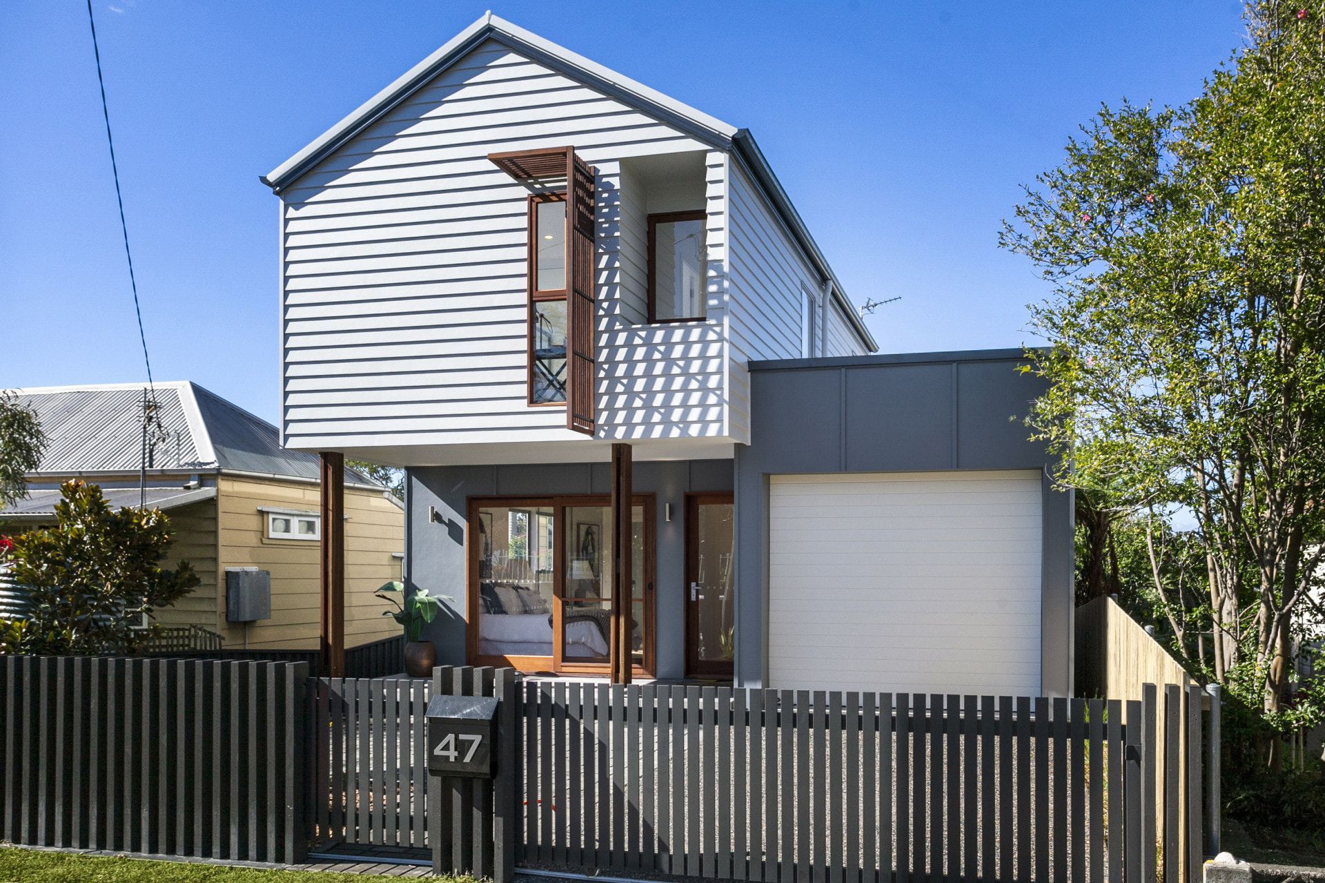 Modern house with grey and white siding, wooden fence and garage door — Envisage Construction and Design in Mountain, NSW