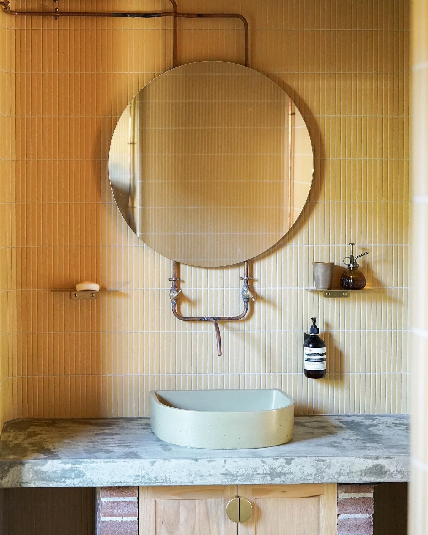 Bathroom With Round Mirror, Copper Pipes, Concrete Counter — Envisage Construction and Design in Mollymook, NSW