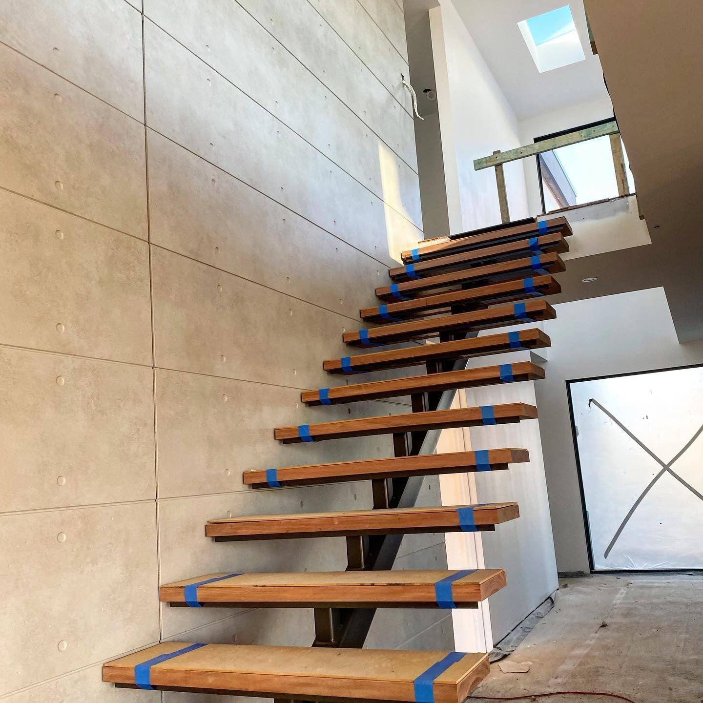 Wooden Floating Staircase With Blue Tape on the Steps — Envisage Construction and Design in Jervis Bay, NSW