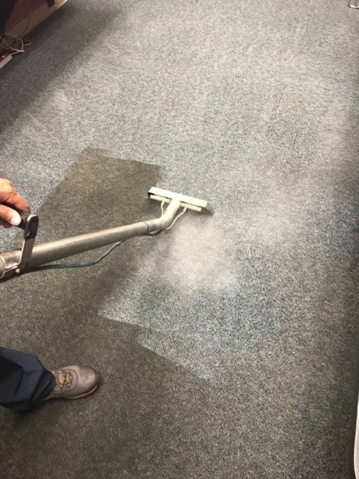 A person is cleaning a carpet with a vacuum cleaner.