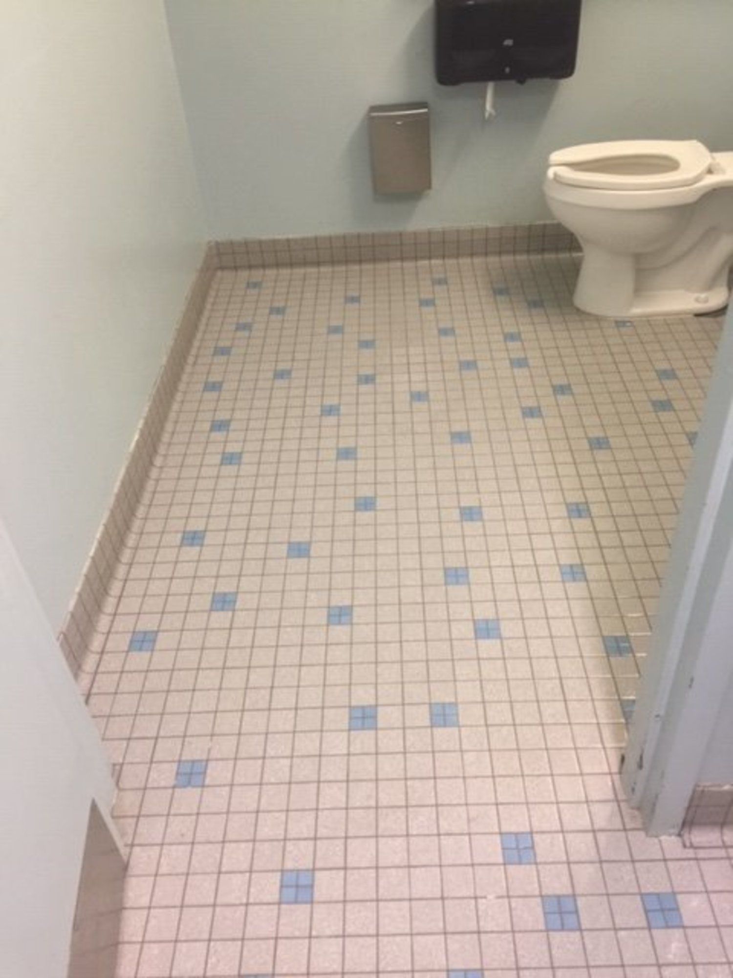 A bathroom with a toilet and a tiled floor