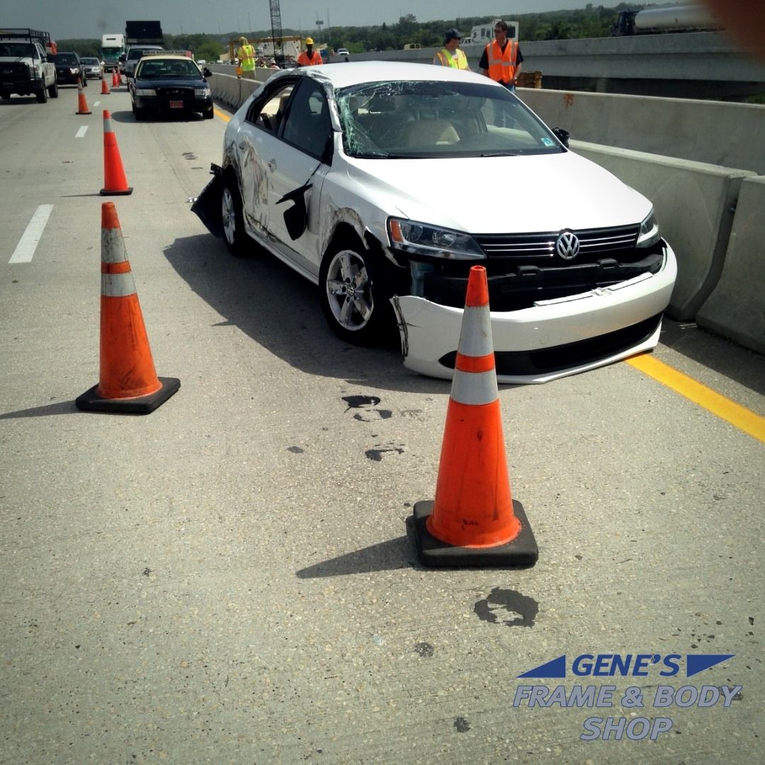 A white car is sitting on a highway next to orange cones