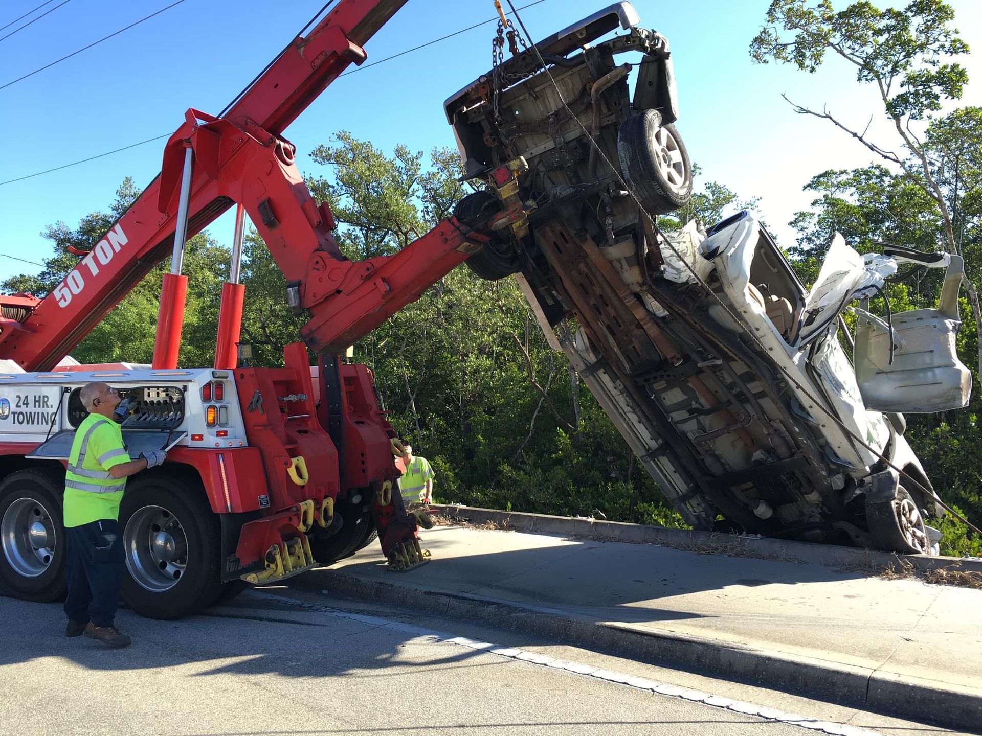 A tow truck is lifting a car that has fallen off the road