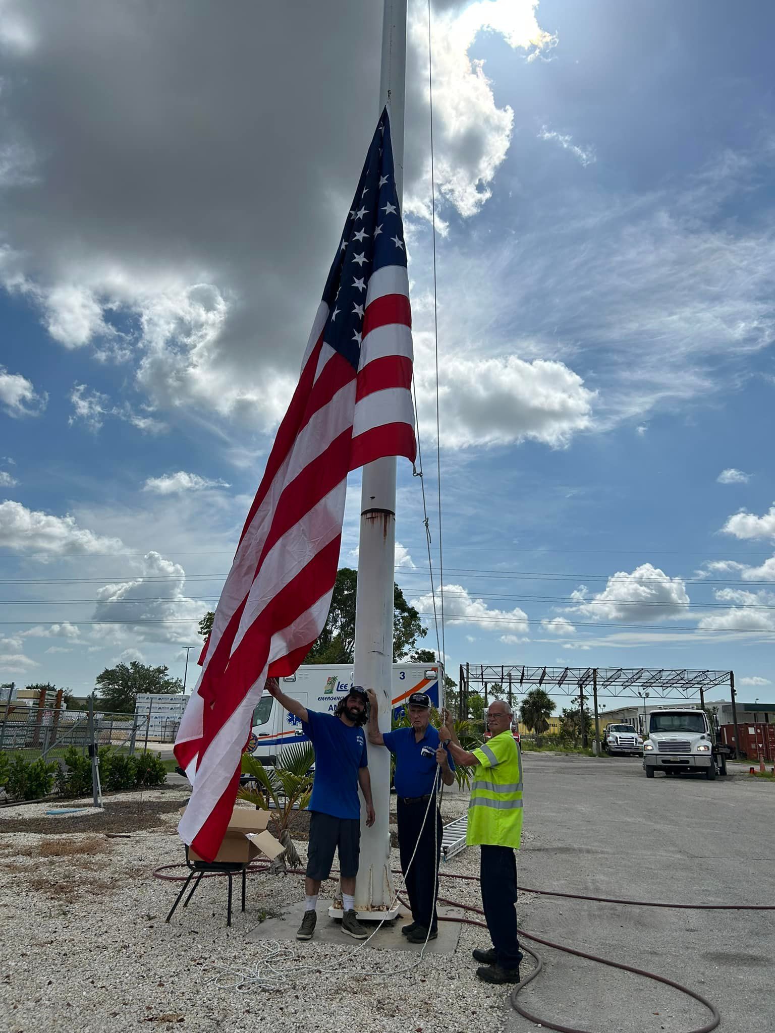 A group of men are raising an american flag on a pole.
