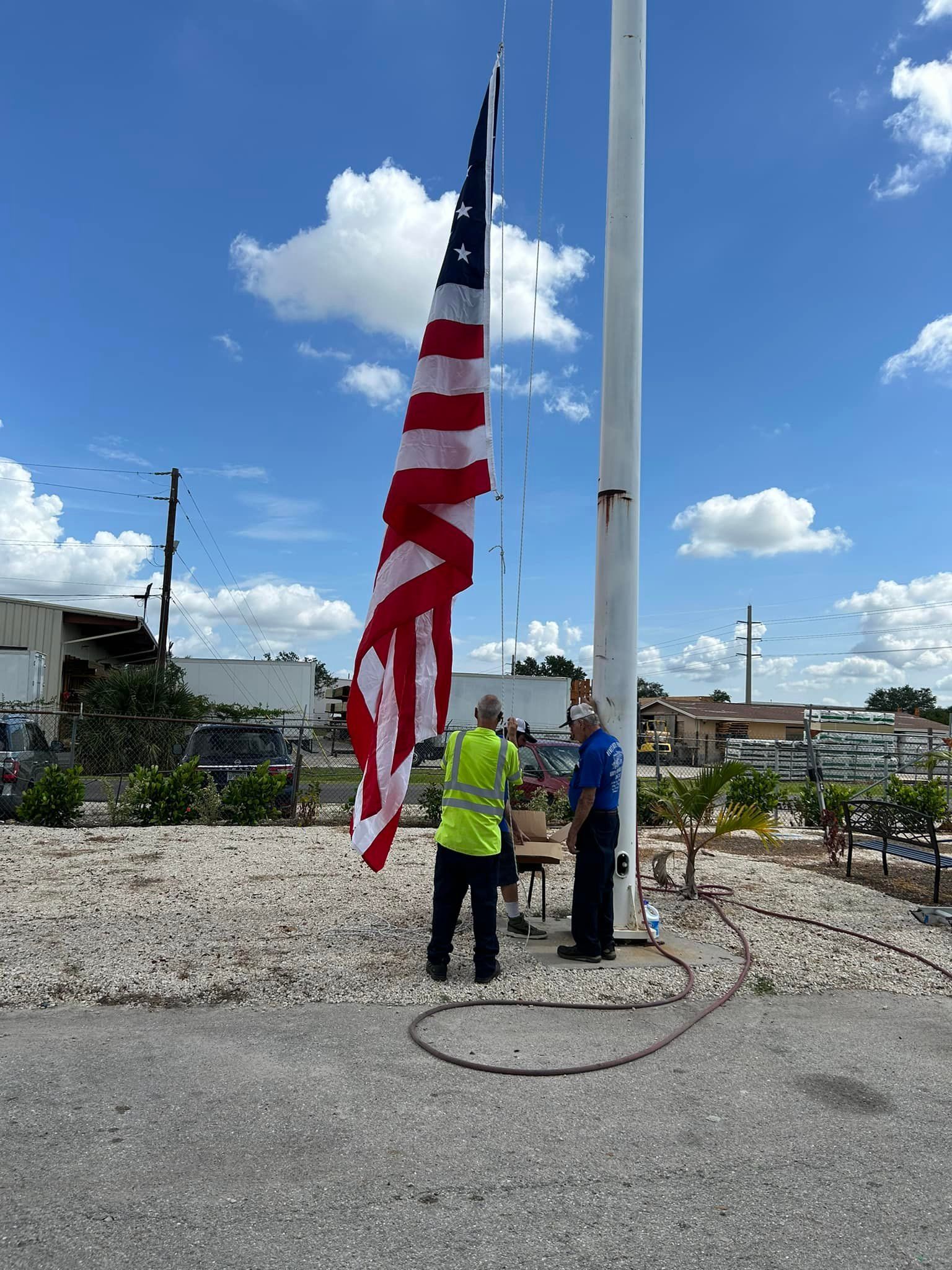 Two men are standing next to an american flag on a pole.