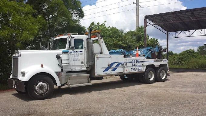 White tow truck parked outside, bright sunny day.