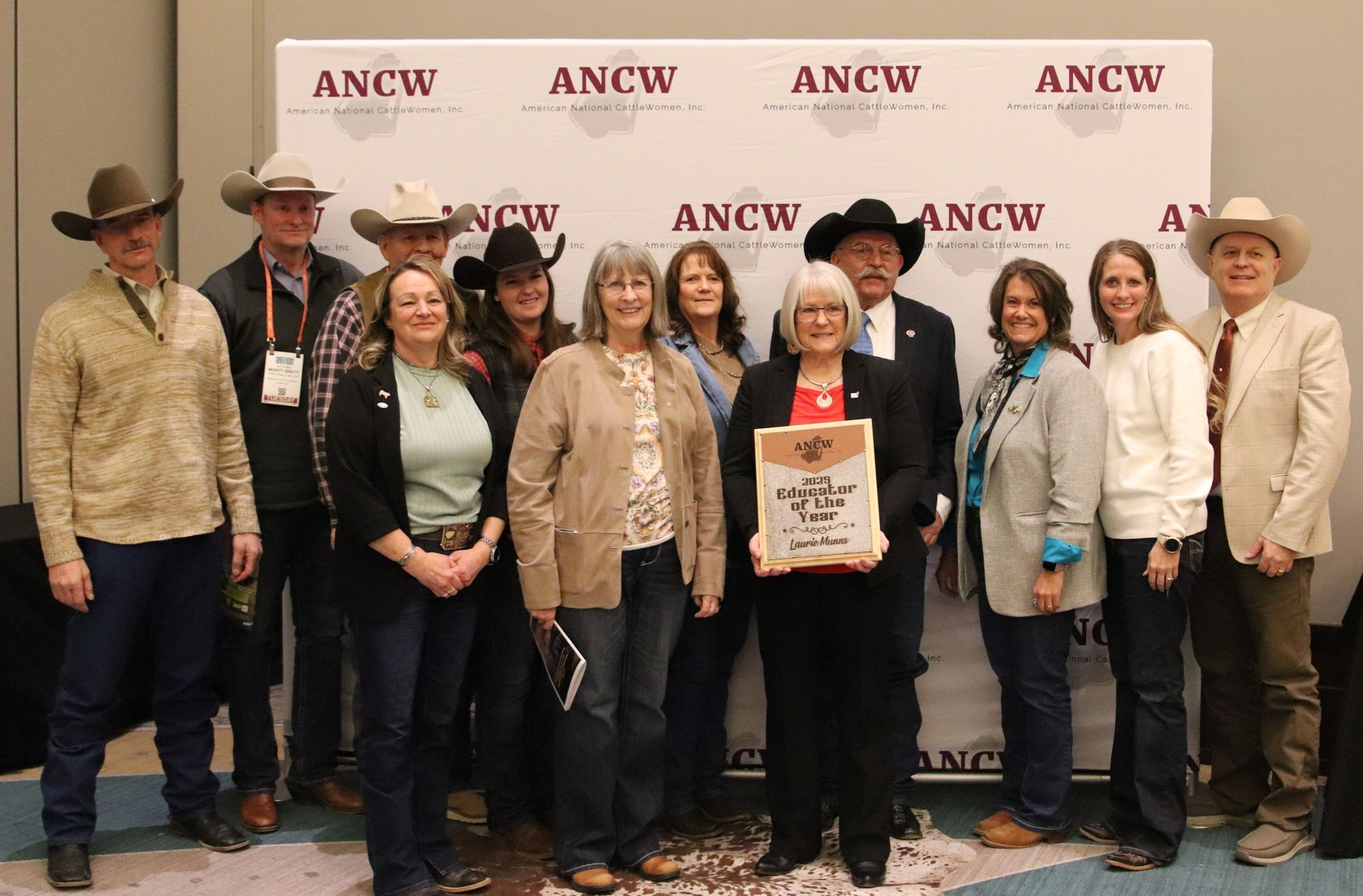 Five women smiling, posing behind illuminated 